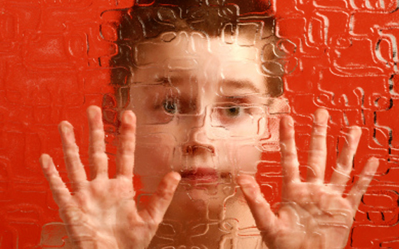 Foto che rappresenta la difficoltà di comunicazione di un bambino autistico attraverso l'immagine vista da dietro un vetro.