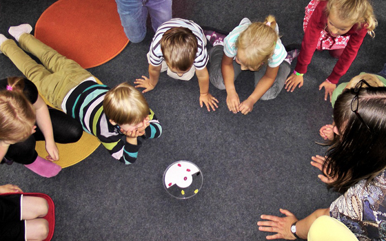 Bambini in cerchio che giocano a scuola. Interprete LIS.